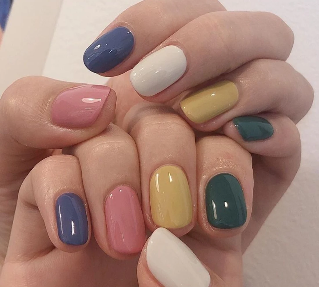 Mismatched manicure with every nail a different colour — indigo, white, mustard, pine and pink